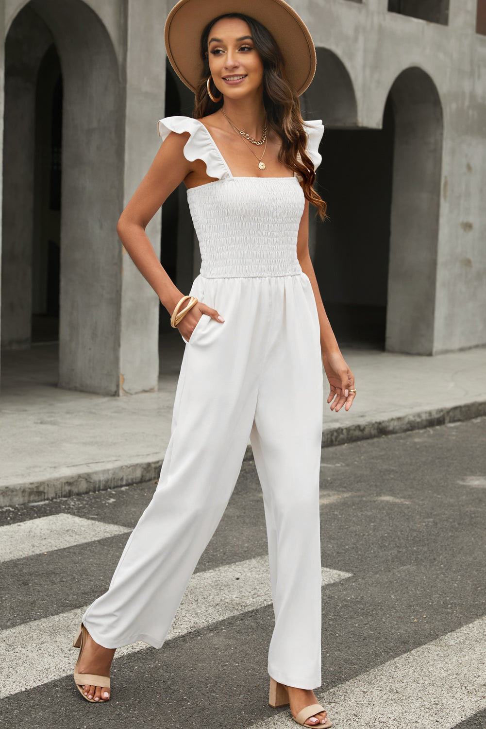 A stylish black jumpsuit featuring flutter sleeves, a smocked bodice, and wide leg bottoms, perfect for any occasion.