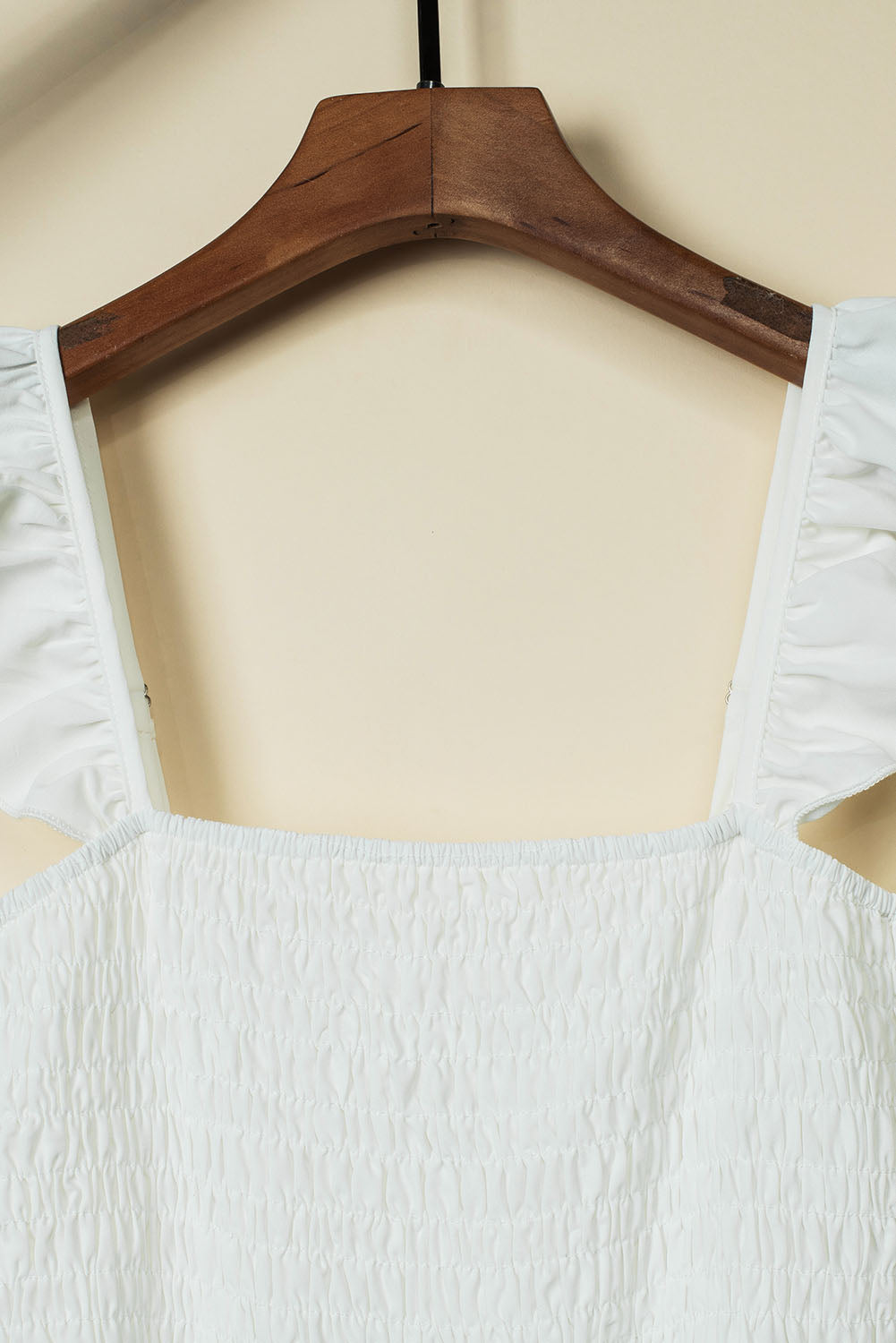 A stylish black jumpsuit featuring flutter sleeves, a smocked bodice, and wide leg bottoms, perfect for any occasion.