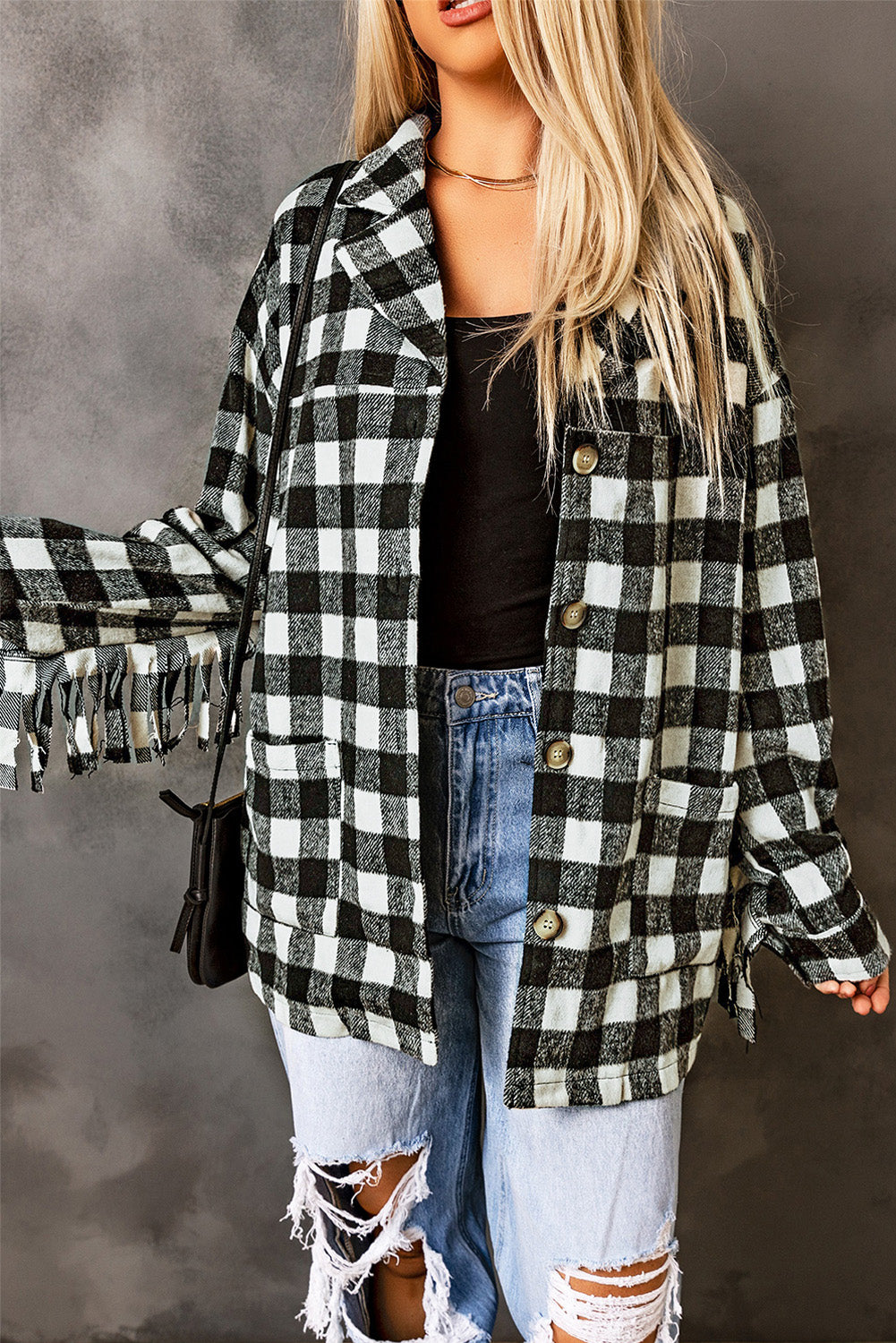 Black fringed plaid print shacket featuring a classic black and white pattern, collared neckline, and stylish fringe details on sleeves.