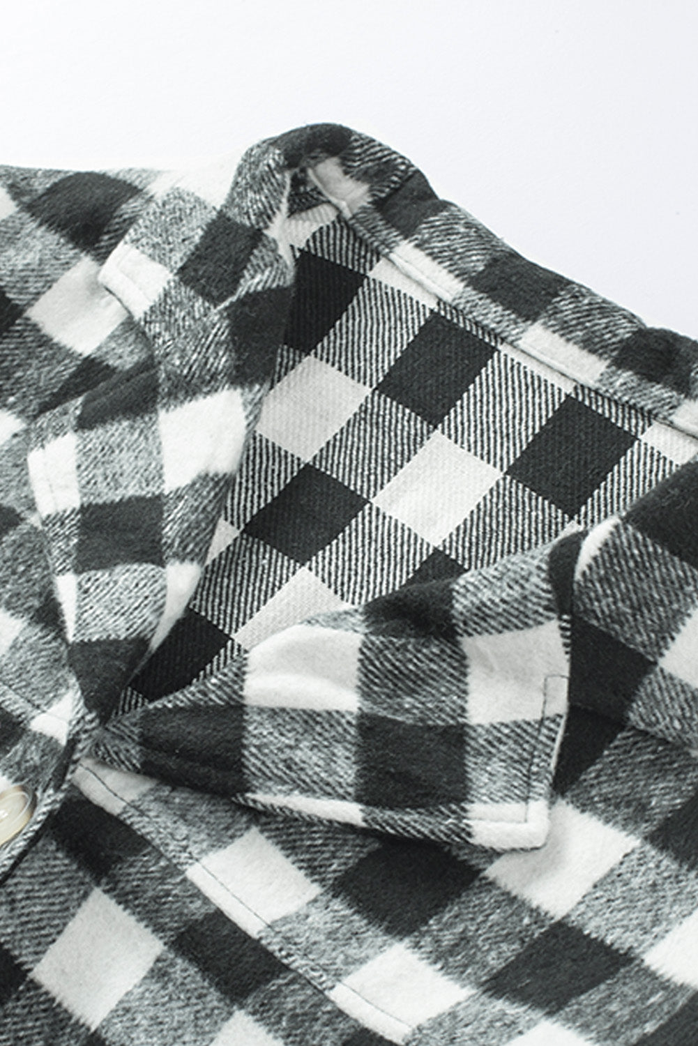 Black fringed plaid print shacket featuring a classic black and white pattern, collared neckline, and stylish fringe details on sleeves.