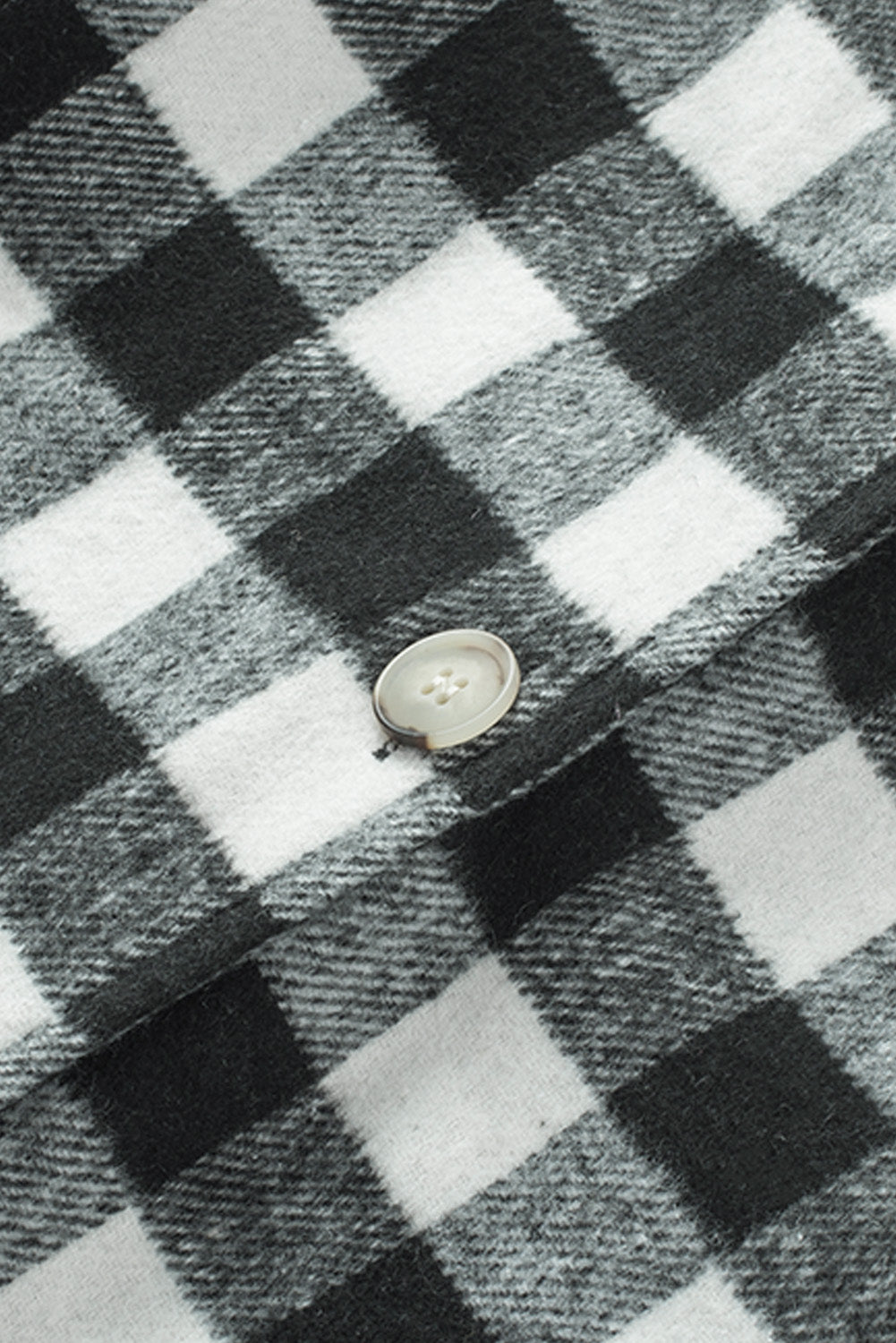 Black fringed plaid print shacket featuring a classic black and white pattern, collared neckline, and stylish fringe details on sleeves.