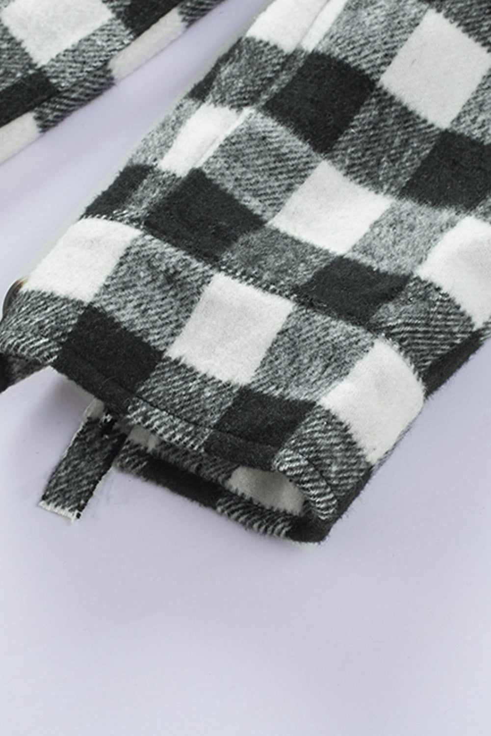 Black fringed plaid print shacket featuring a classic black and white pattern, collared neckline, and stylish fringe details on sleeves.