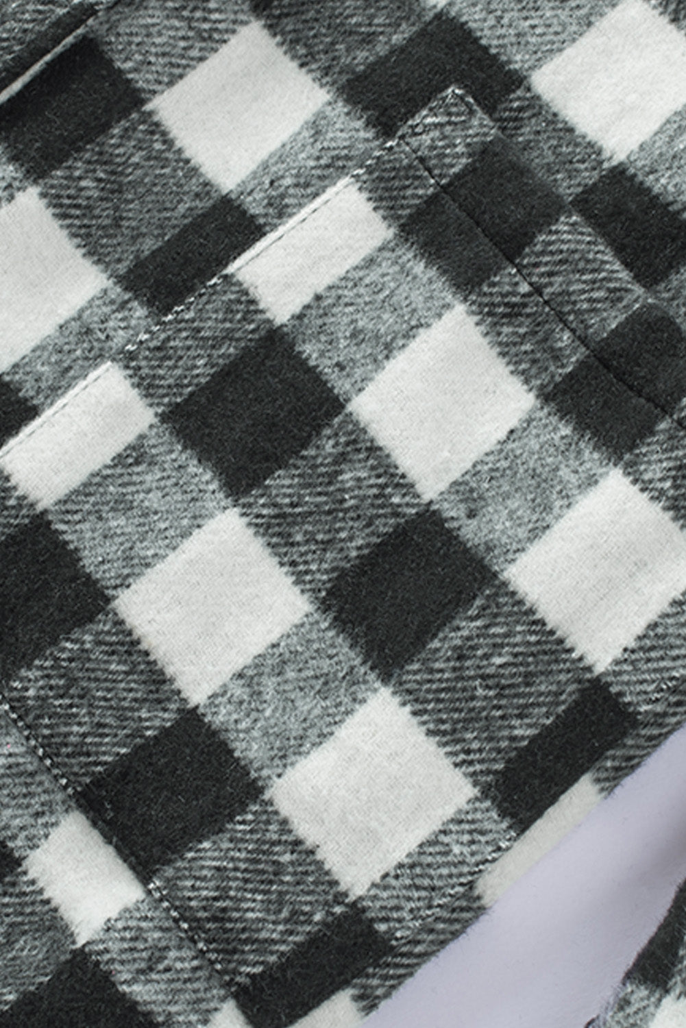 Black fringed plaid print shacket featuring a classic black and white pattern, collared neckline, and stylish fringe details on sleeves.