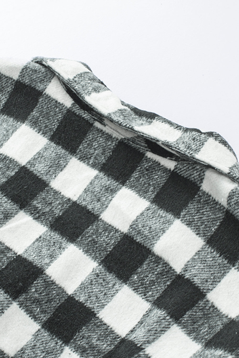Black fringed plaid print shacket featuring a classic black and white pattern, collared neckline, and stylish fringe details on sleeves.