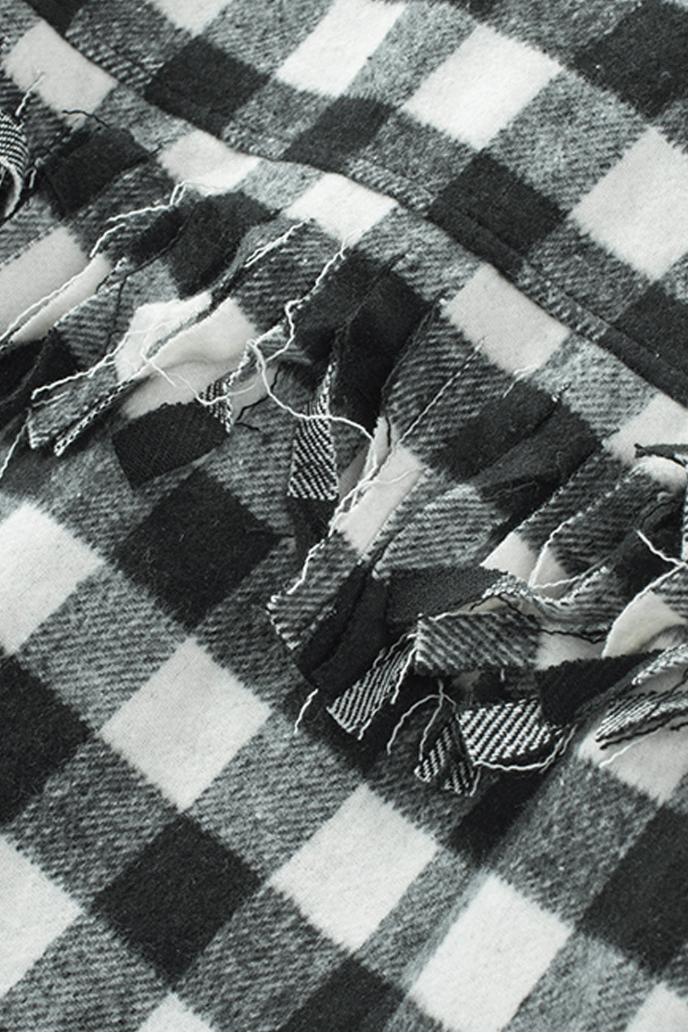 Black fringed plaid print shacket featuring a classic black and white pattern, collared neckline, and stylish fringe details on sleeves.