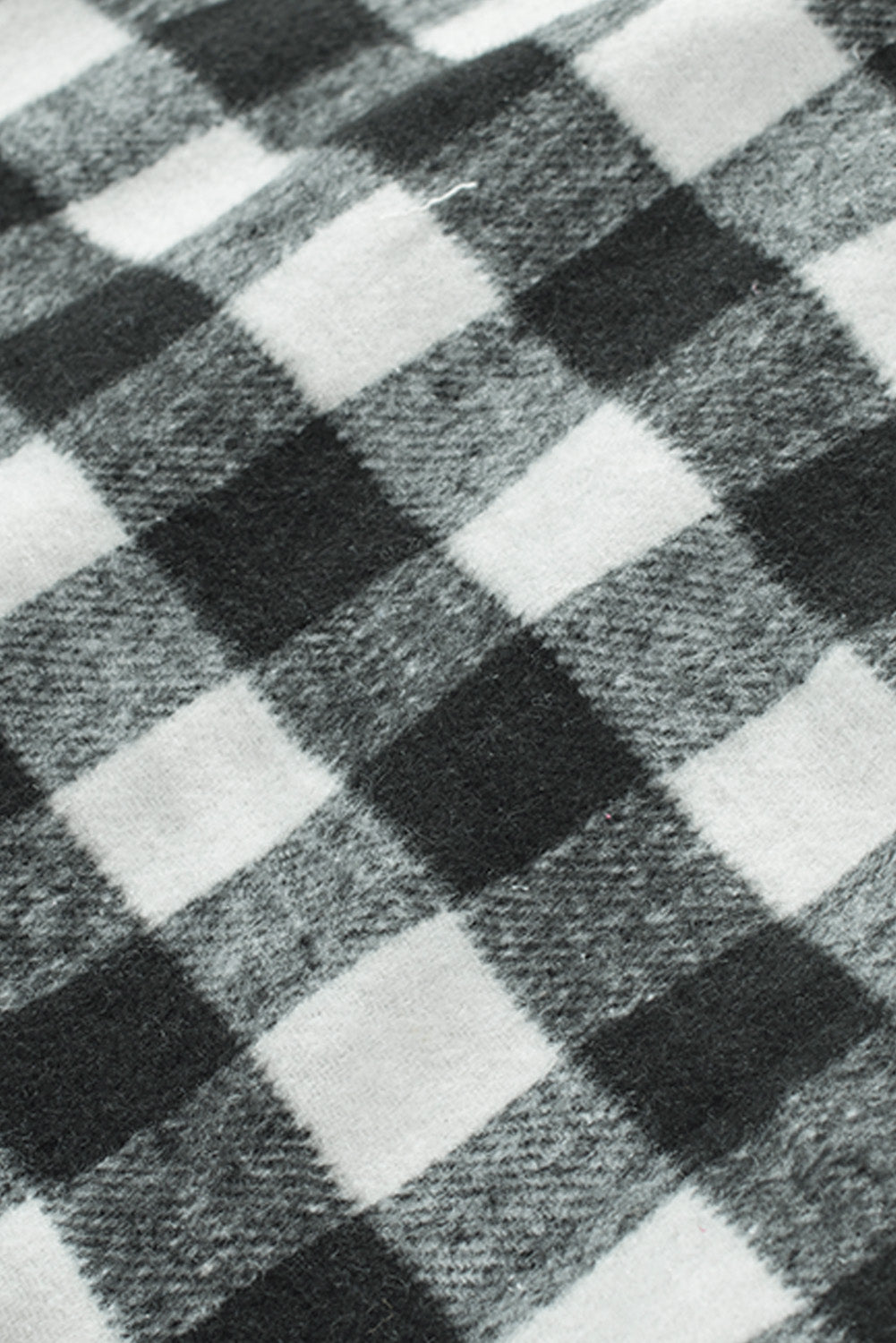 Black fringed plaid print shacket featuring a classic black and white pattern, collared neckline, and stylish fringe details on sleeves.