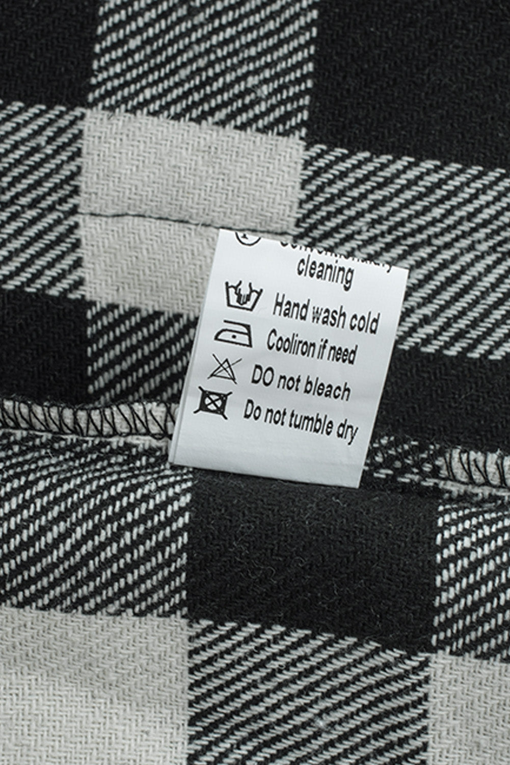 Black fringed plaid print shacket featuring a classic black and white pattern, collared neckline, and stylish fringe details on sleeves.