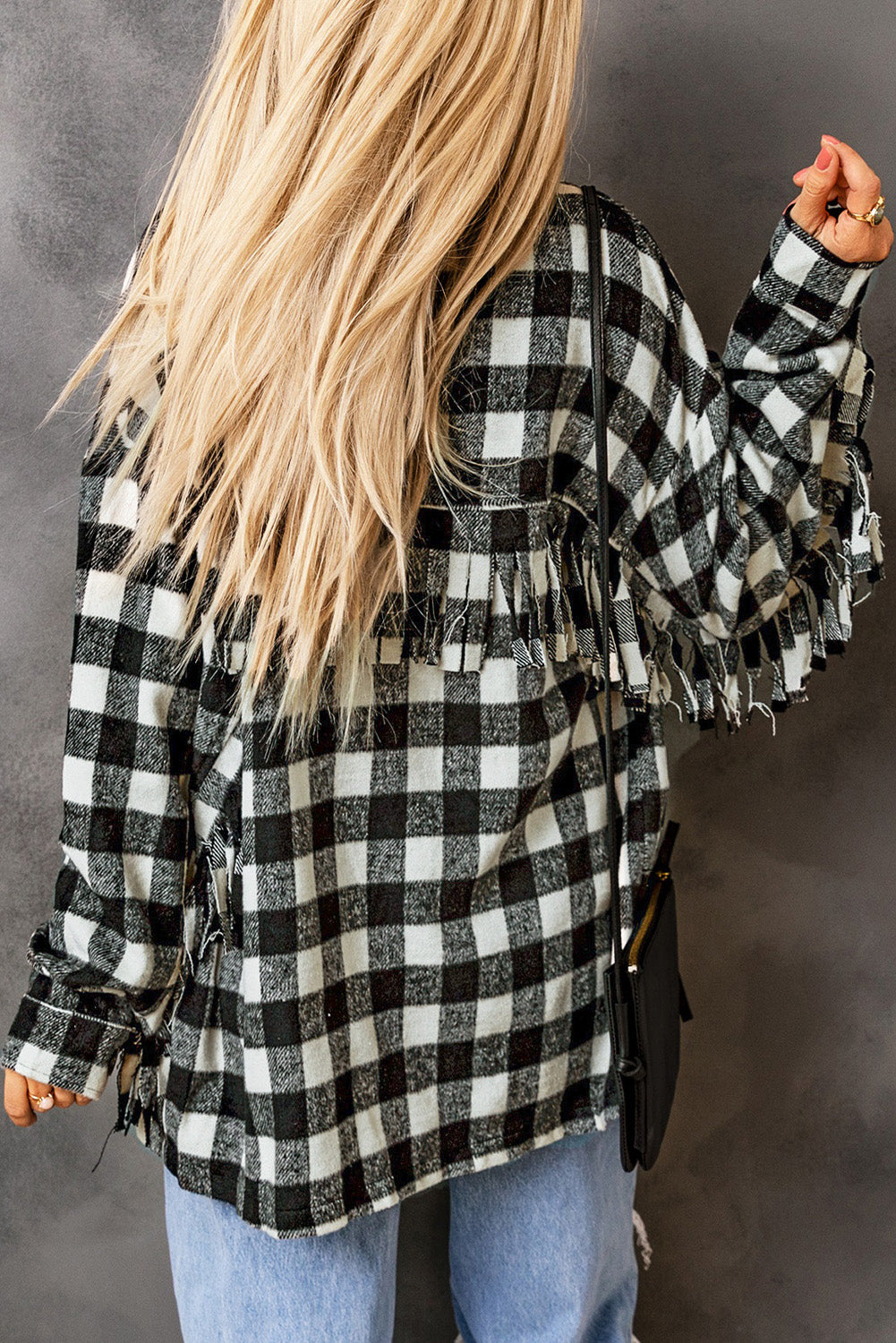 Black fringed plaid print shacket featuring a classic black and white pattern, collared neckline, and stylish fringe details on sleeves.