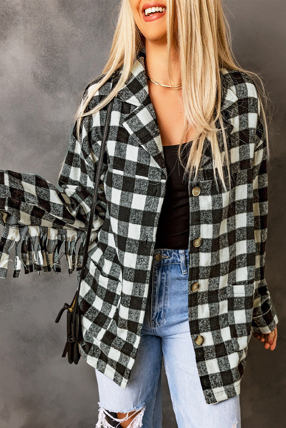 Black fringed plaid print shacket featuring a classic black and white pattern, collared neckline, and stylish fringe details on sleeves.
