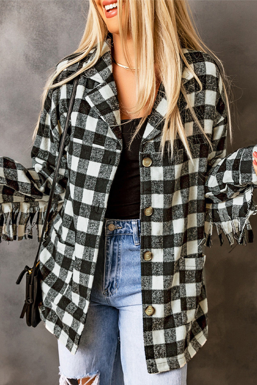 Black fringed plaid print shacket featuring a classic black and white pattern, collared neckline, and stylish fringe details on sleeves.