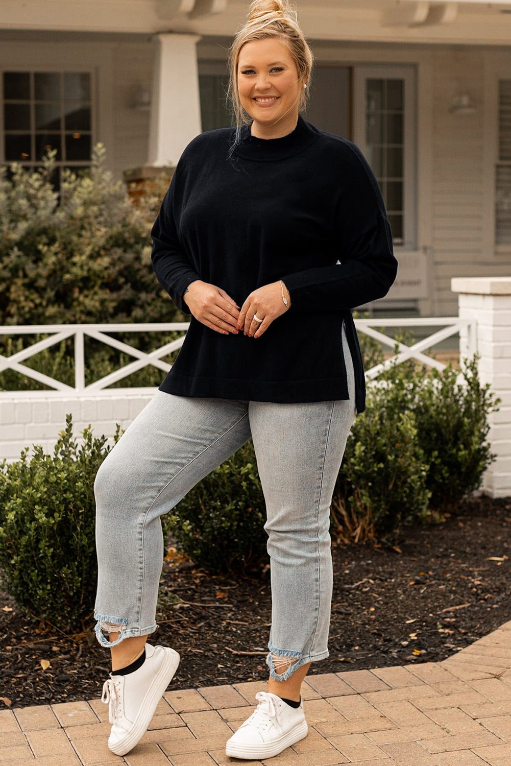 Black plus size loose sweater with side slits and high neck design, showcasing a relaxed fit and stylish look.