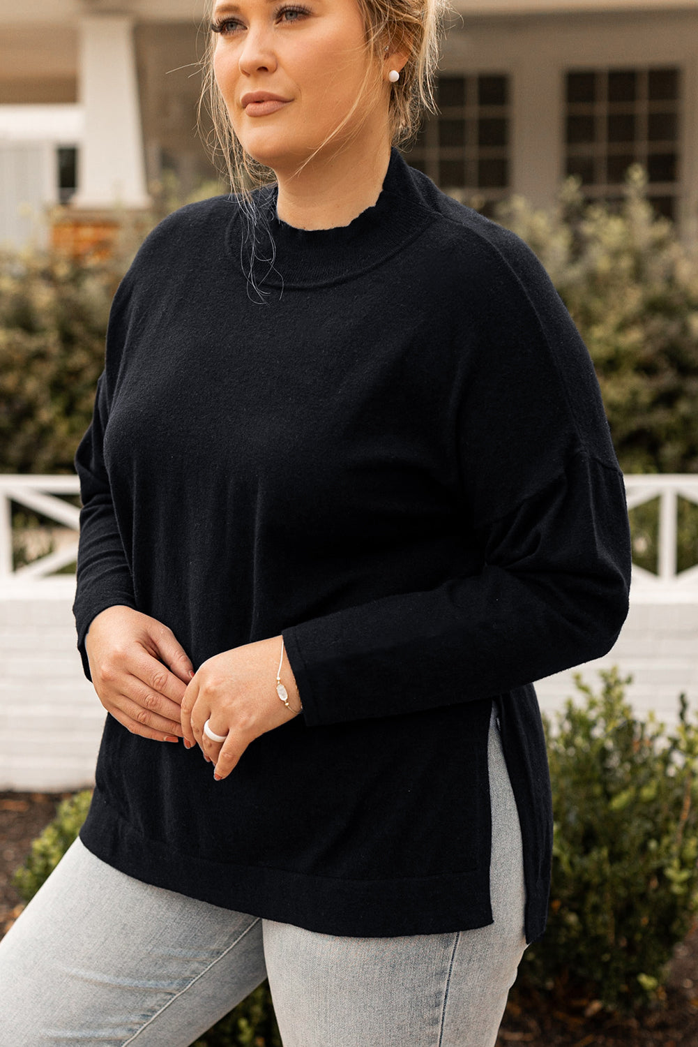Black plus size loose sweater with side slits and high neck design, showcasing a relaxed fit and stylish look.