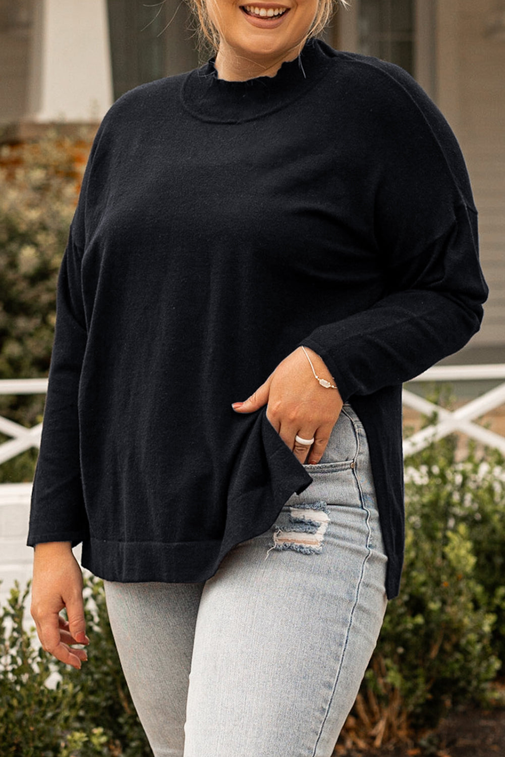 Black plus size loose sweater with side slits and high neck design, showcasing a relaxed fit and stylish look.