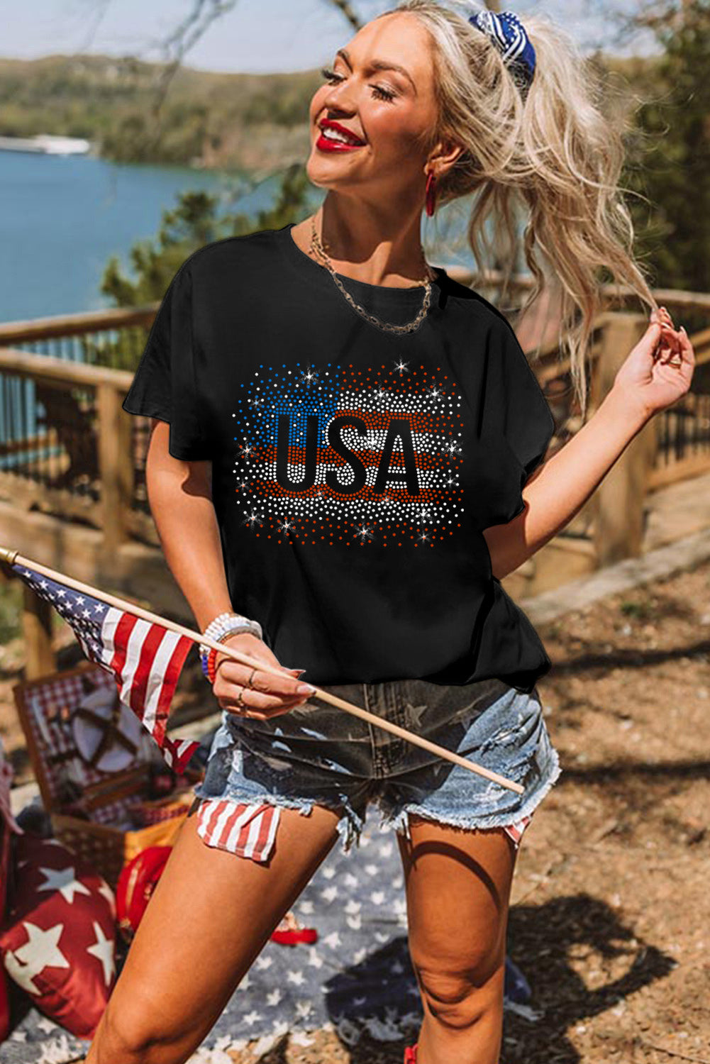 Black t-shirt featuring a rhinestone graphic of the American flag, showcasing a stylish patriotic design.