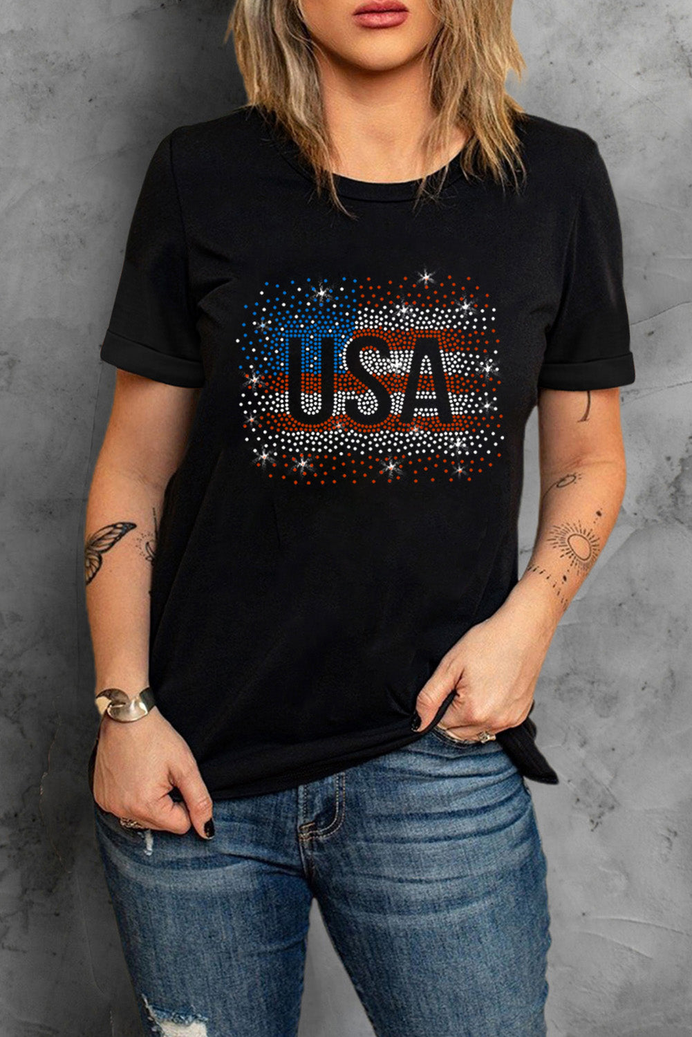 Black t-shirt featuring a rhinestone graphic of the American flag, showcasing a stylish patriotic design.
