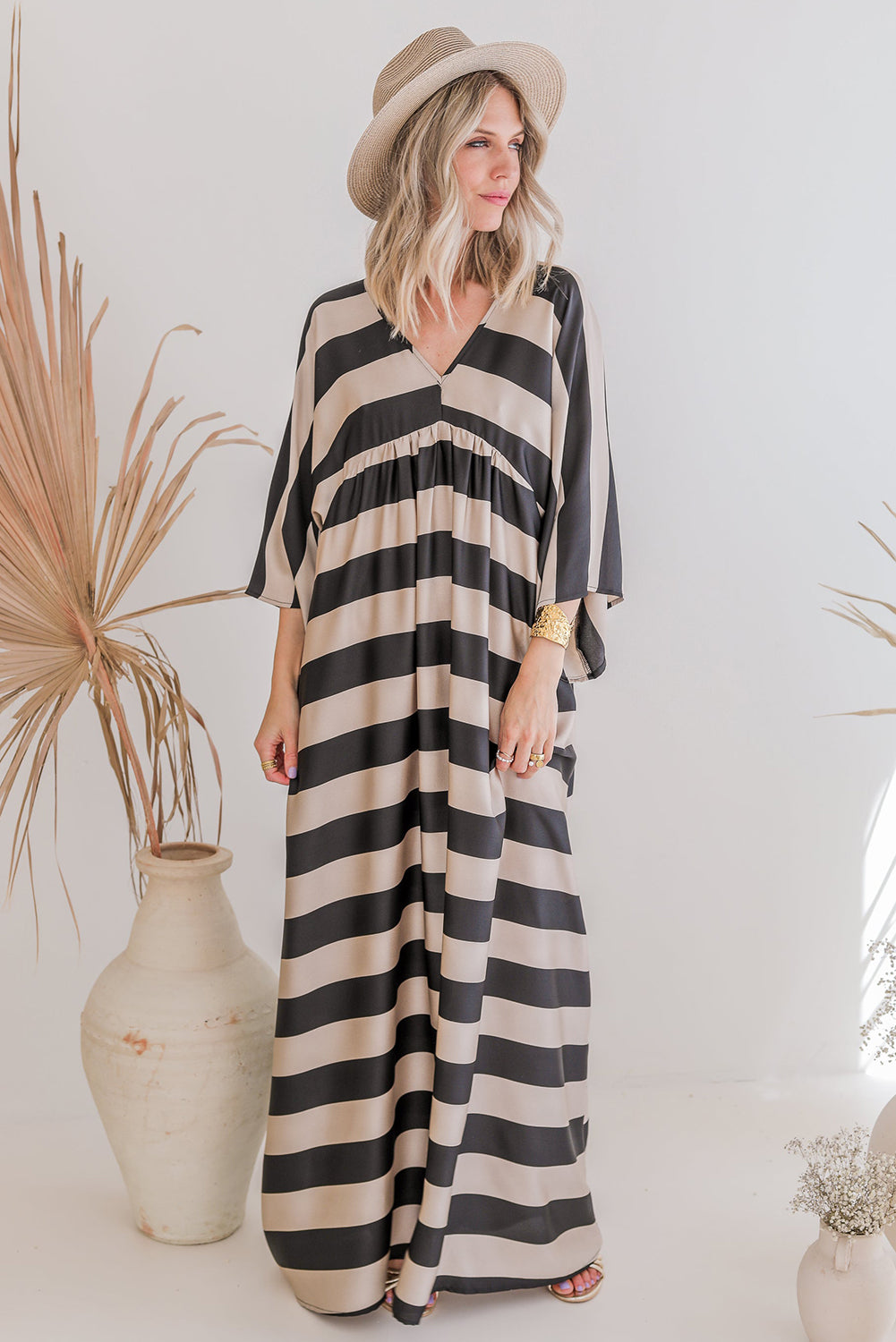 A stylish black maxi dress featuring a v neck and kimono sleeves, adorned with a classic striped print, perfect for elegant occasions.