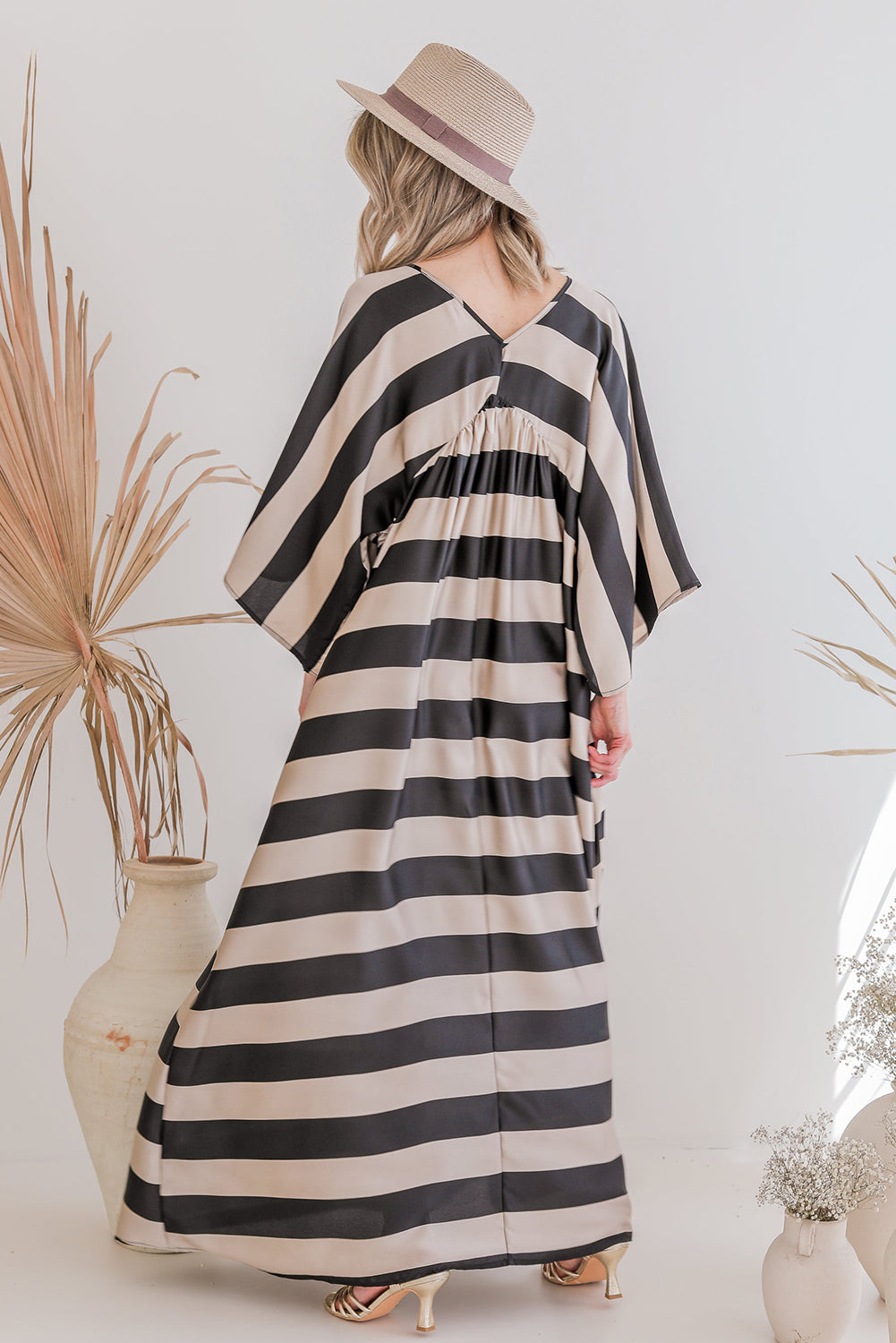 A stylish black maxi dress featuring a v neck and kimono sleeves, adorned with a classic striped print, perfect for elegant occasions.