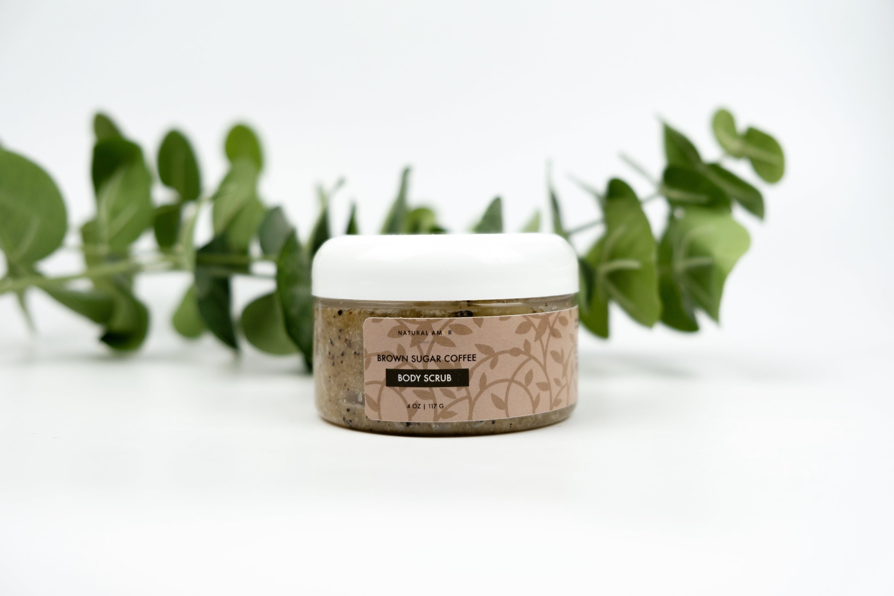 Brown Sugar Coffee Body Scrub in a clear jar with a wooden spoon, showcasing its rich texture and natural ingredients.