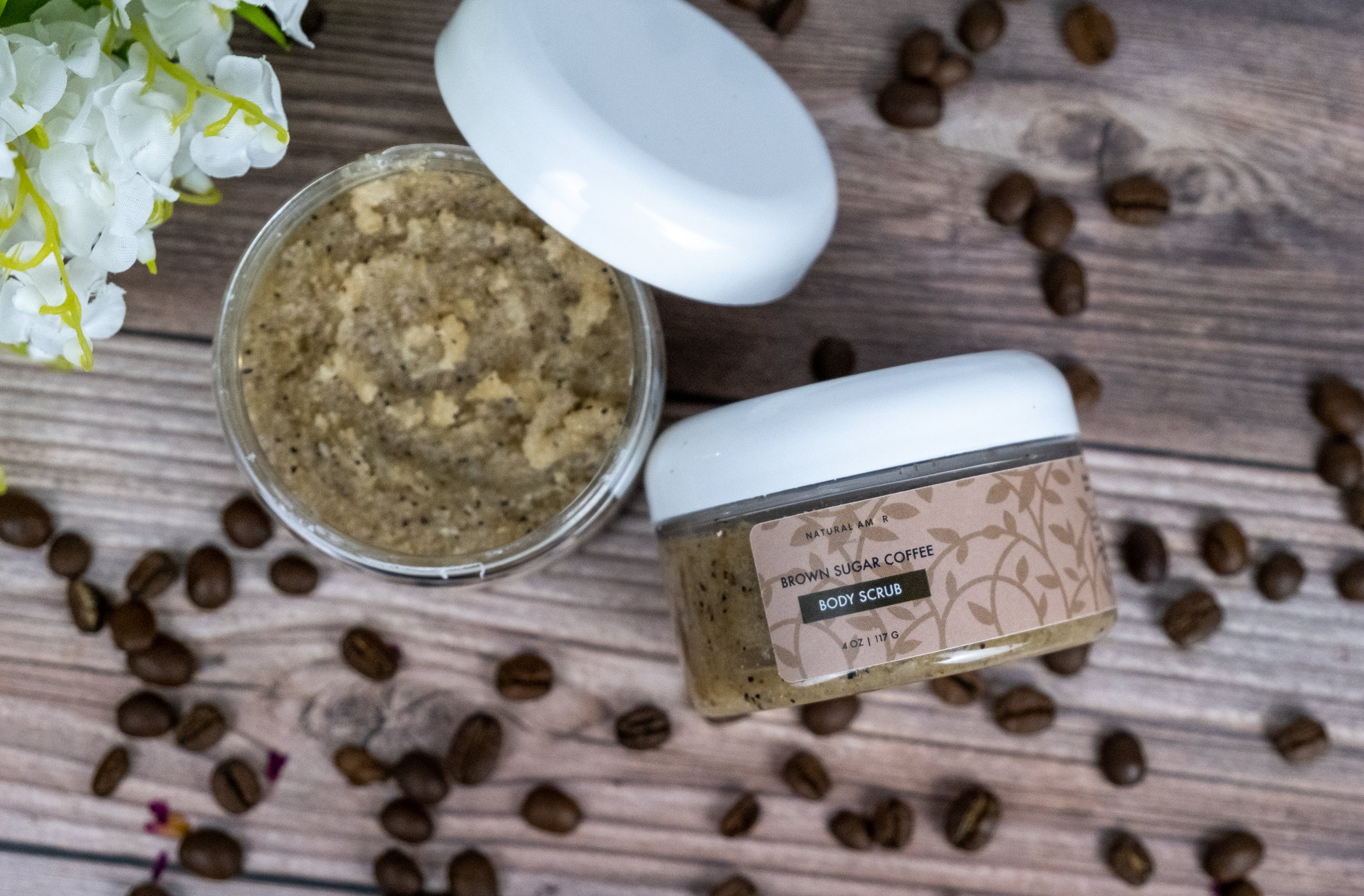 Brown Sugar Coffee Body Scrub in a clear jar with a wooden spoon, showcasing its rich texture and natural ingredients.