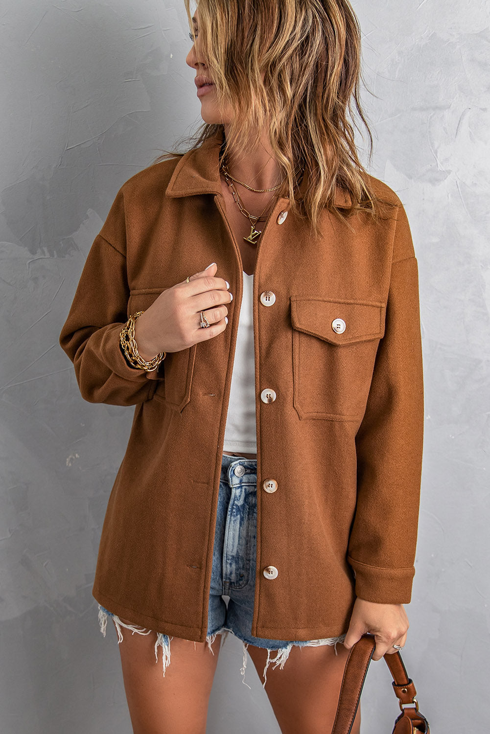 A stylish brown coat featuring a turn down collar, buttoned closure, and flap pockets, designed for a baggy fit.