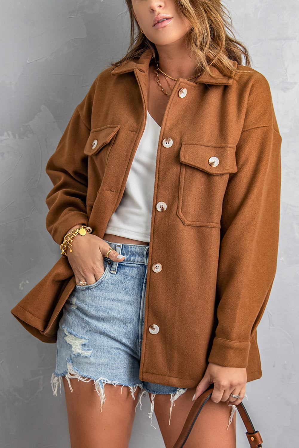 A stylish brown coat featuring a turn down collar, buttoned closure, and flap pockets, designed for a baggy fit.