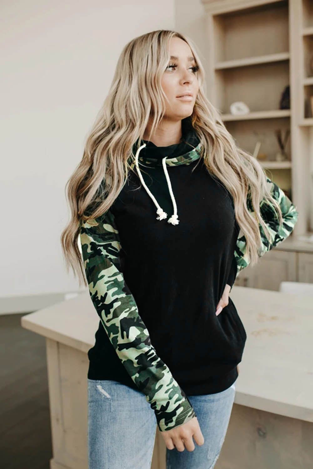 A stylish camouflage print raglan sleeve hoodie featuring a double hood and thumb holes, perfect for modern ladies in fall.