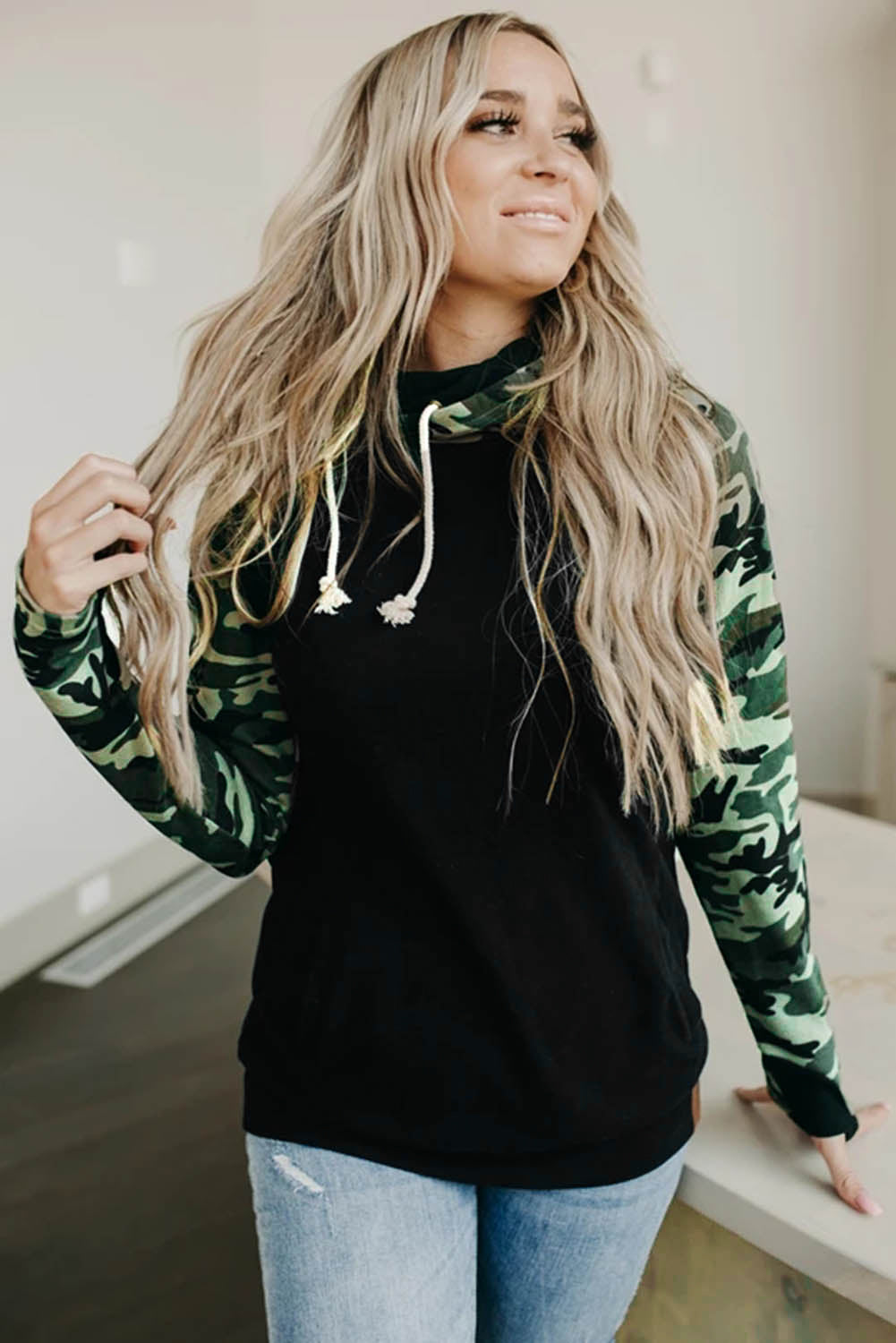 A stylish camouflage print raglan sleeve hoodie featuring a double hood and thumb holes, perfect for modern ladies in fall.