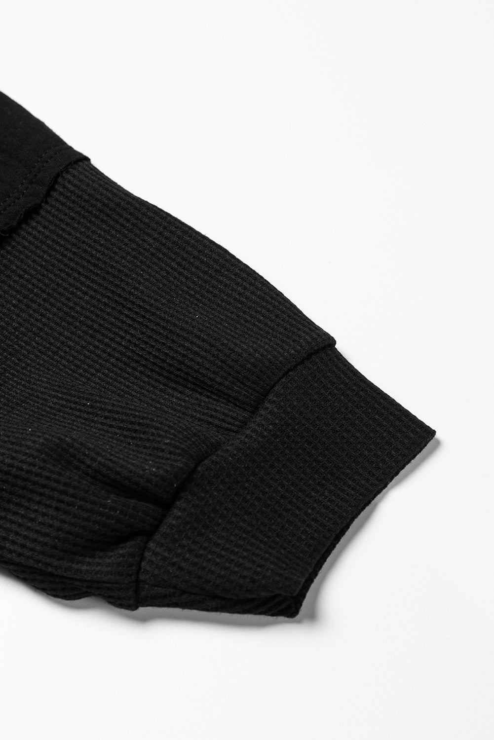 Dark brown waffle knit top with exposed seams and bubble sleeves, featuring a chic patchwork design and front pocket.