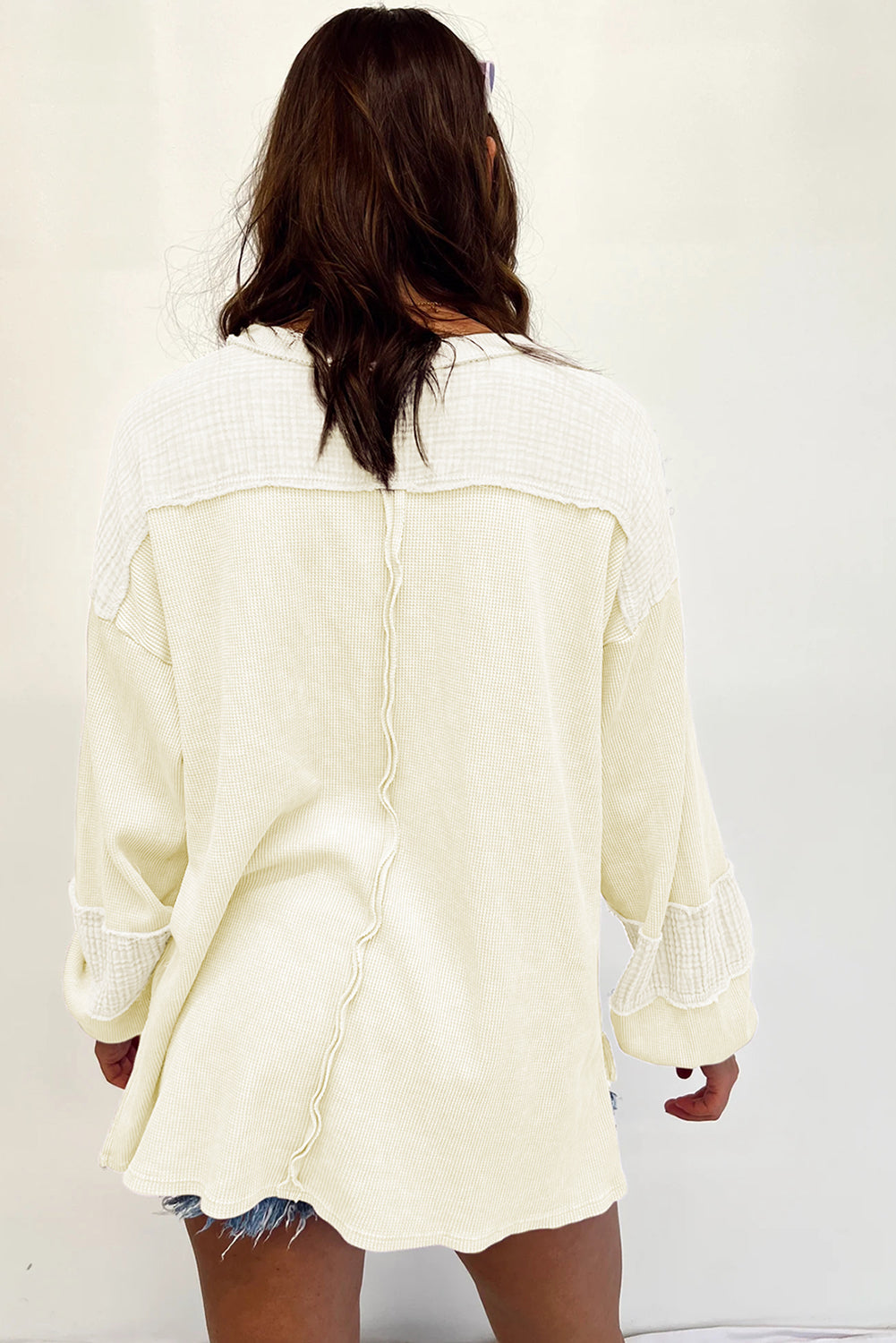 Dark brown waffle knit top with exposed seams and bubble sleeves, featuring a chic patchwork design and front pocket.