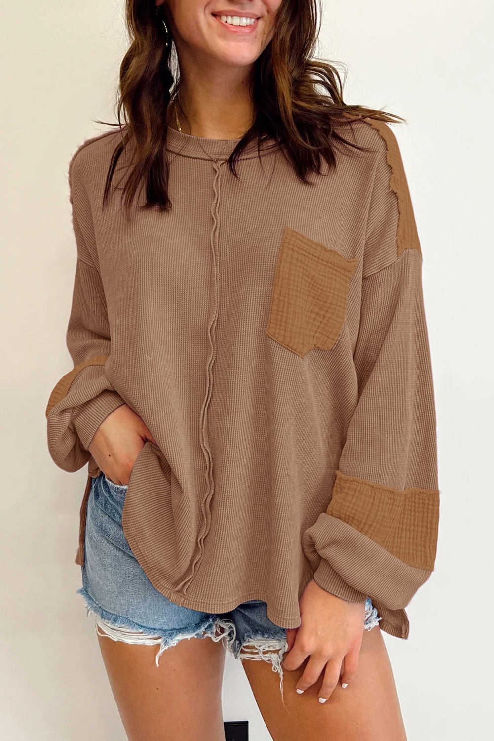 Dark brown waffle knit top with exposed seams and bubble sleeves, featuring a chic patchwork design and front pocket.