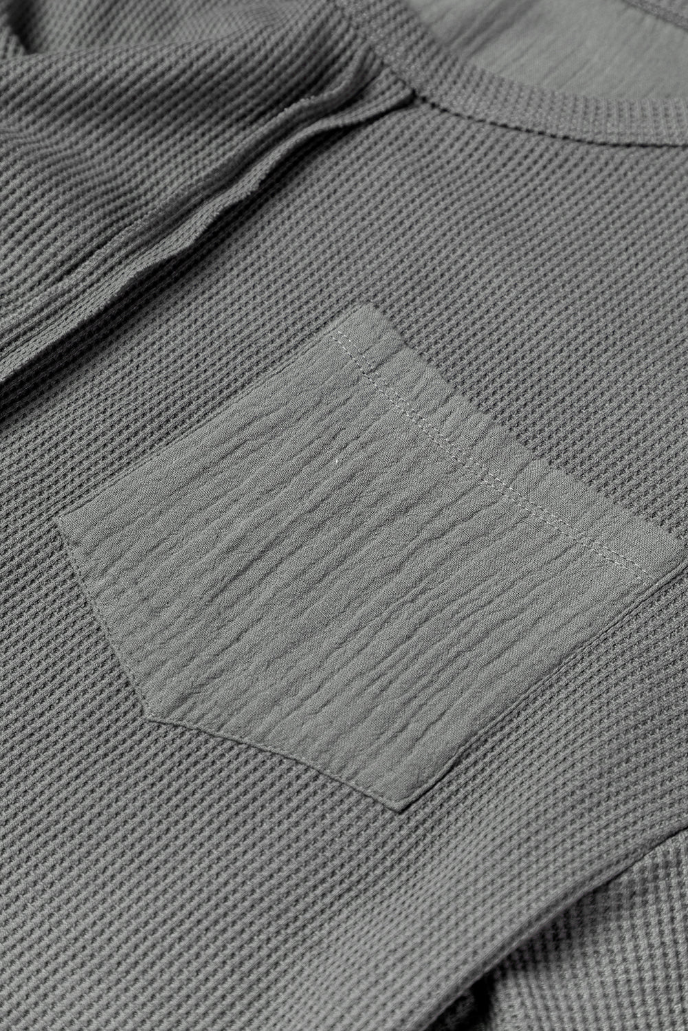 Dark brown waffle knit top with exposed seams and bubble sleeves, featuring a chic patchwork design and front pocket.