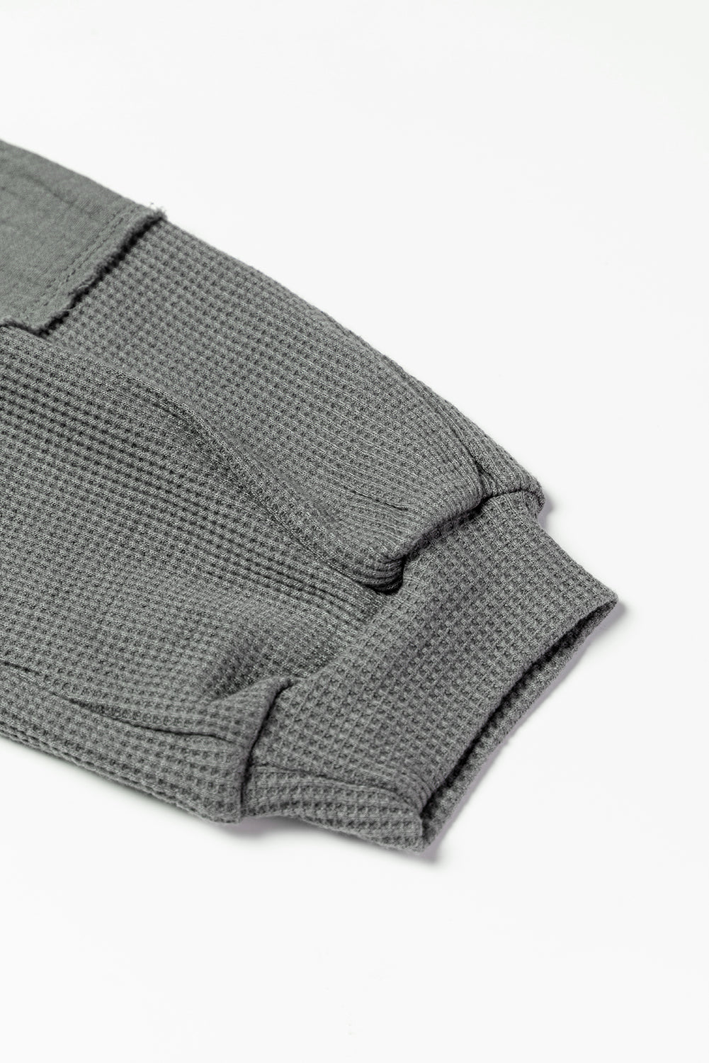 Dark brown waffle knit top with exposed seams and bubble sleeves, featuring a chic patchwork design and front pocket.