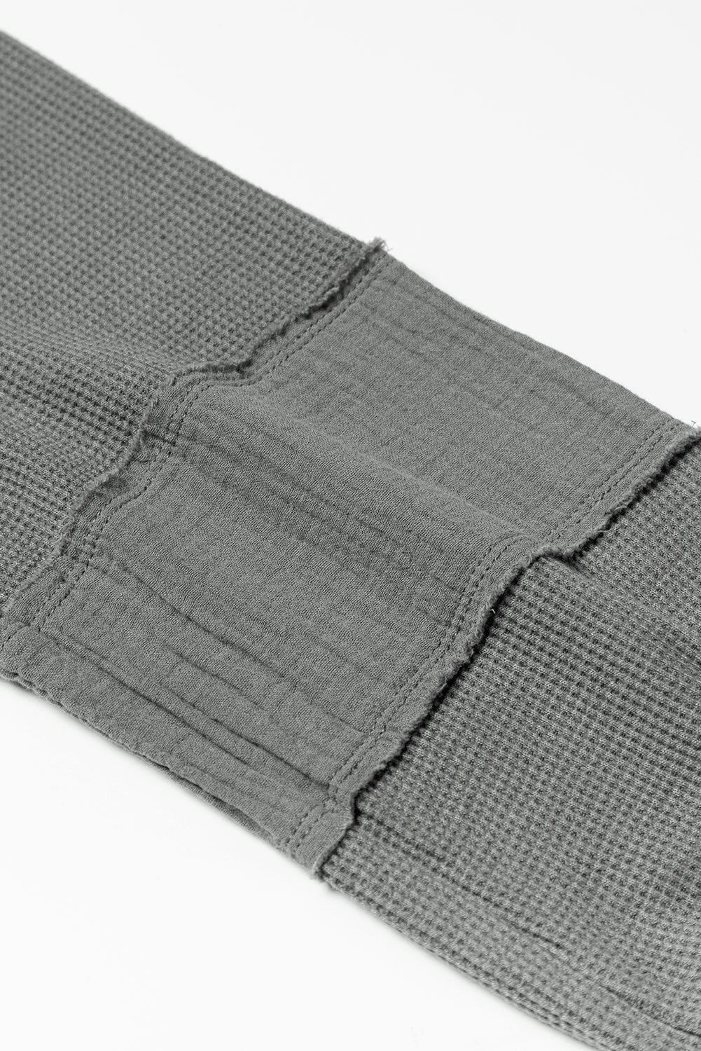 Dark brown waffle knit top with exposed seams and bubble sleeves, featuring a chic patchwork design and front pocket.