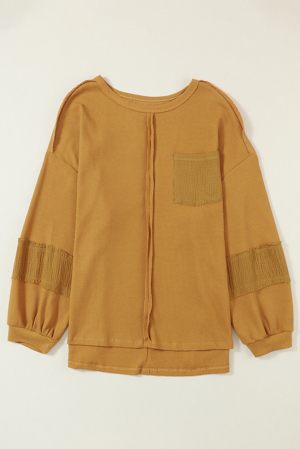 Dark brown waffle knit top with exposed seams and bubble sleeves, featuring a chic patchwork design and front pocket.