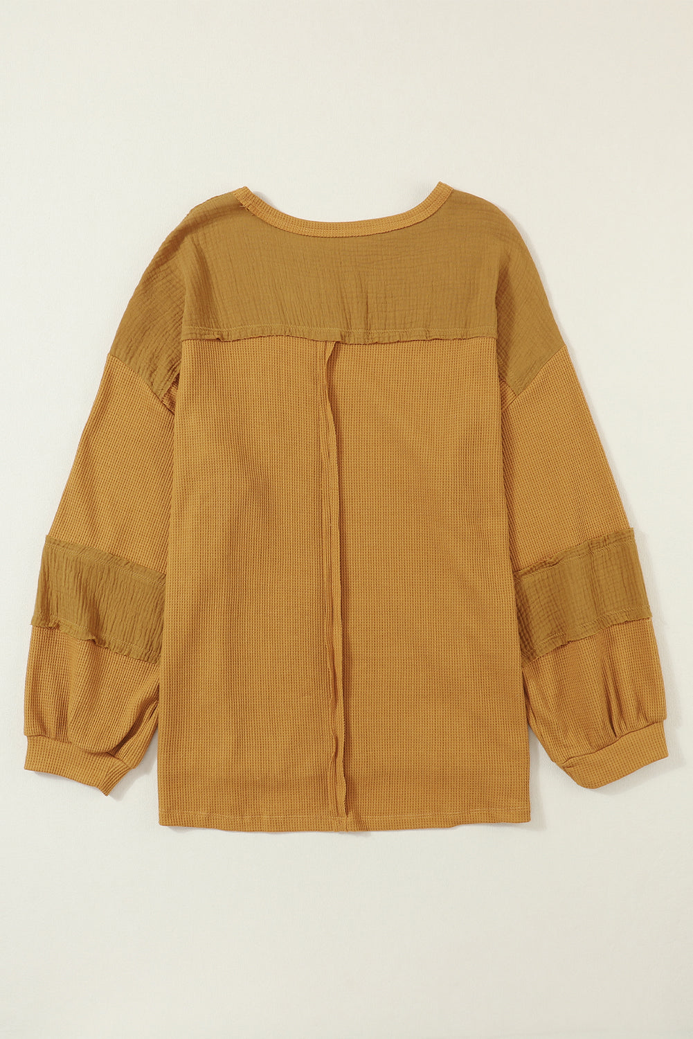 Dark brown waffle knit top with exposed seams and bubble sleeves, featuring a chic patchwork design and front pocket.