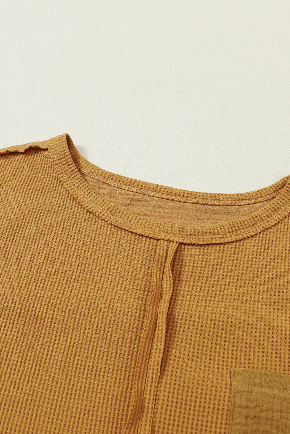 Dark brown waffle knit top with exposed seams and bubble sleeves, featuring a chic patchwork design and front pocket.