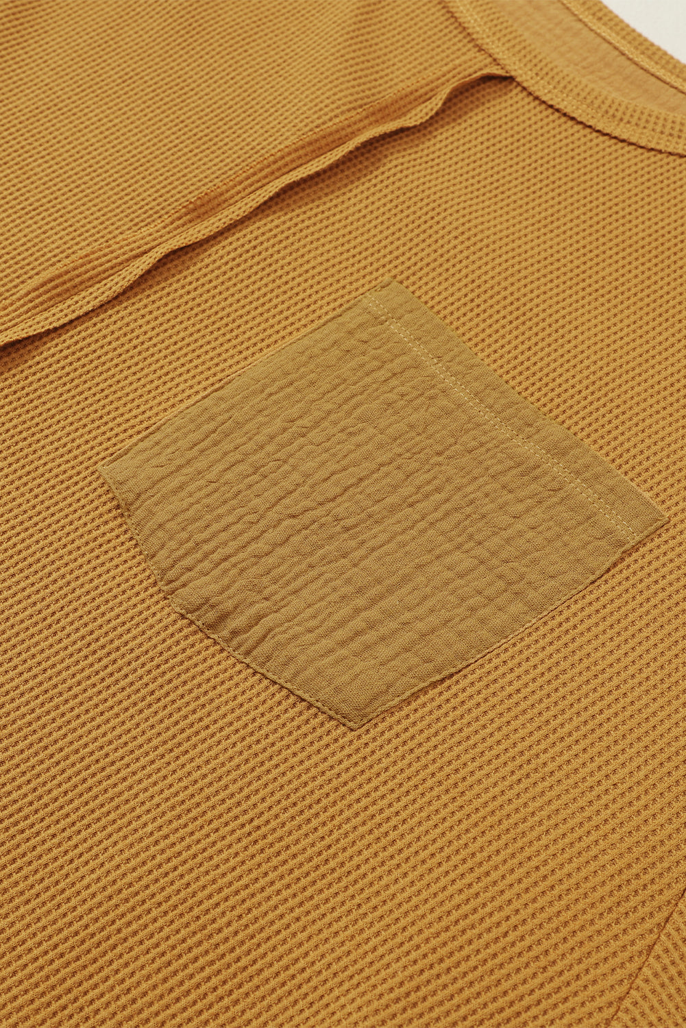 Dark brown waffle knit top with exposed seams and bubble sleeves, featuring a chic patchwork design and front pocket.