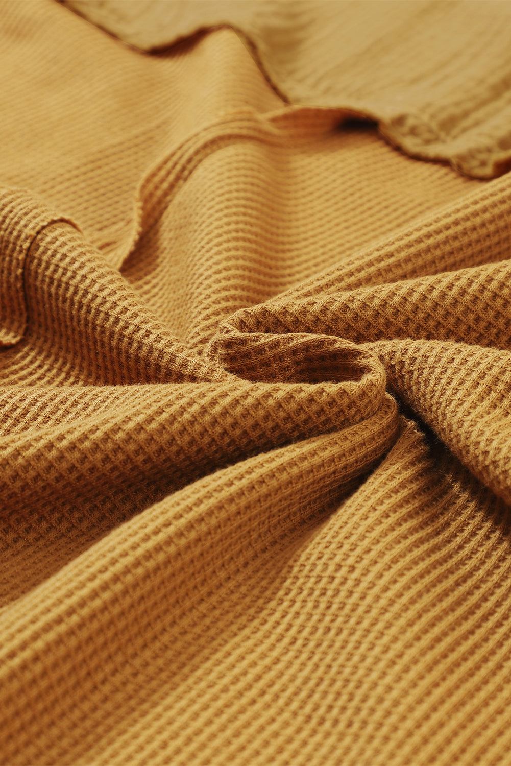 Dark brown waffle knit top with exposed seams and bubble sleeves, featuring a chic patchwork design and front pocket.