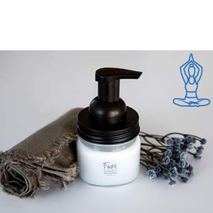 A stylish reusable glass and bronze foaming soap jar filled with natural essential oil hand soap, featuring a blend of invigorating essential oils.