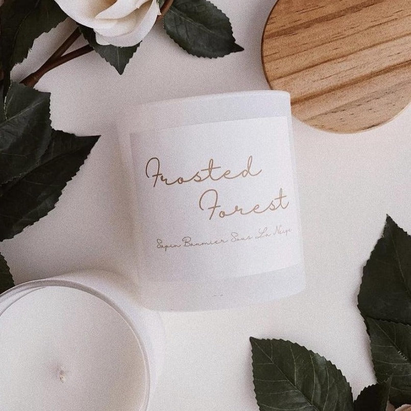 Frosted Forest candle in a glass jar with wooden lid, featuring Blue Spruce and Balsam Fir scent.