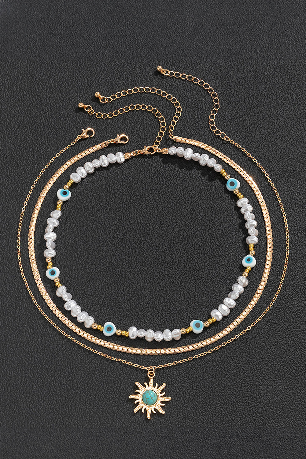 A multi-layered pendant necklace featuring turquoise and pearl beads with a gold sun pendant, elegantly displayed on a soft background.