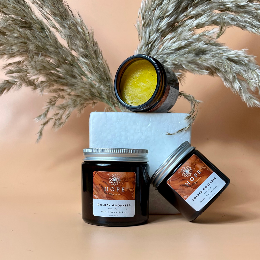 Golden Goodness Glow Mask in a sleek jar, showcasing its rich, creamy texture, surrounded by natural ingredients like pumpkin and papaya.