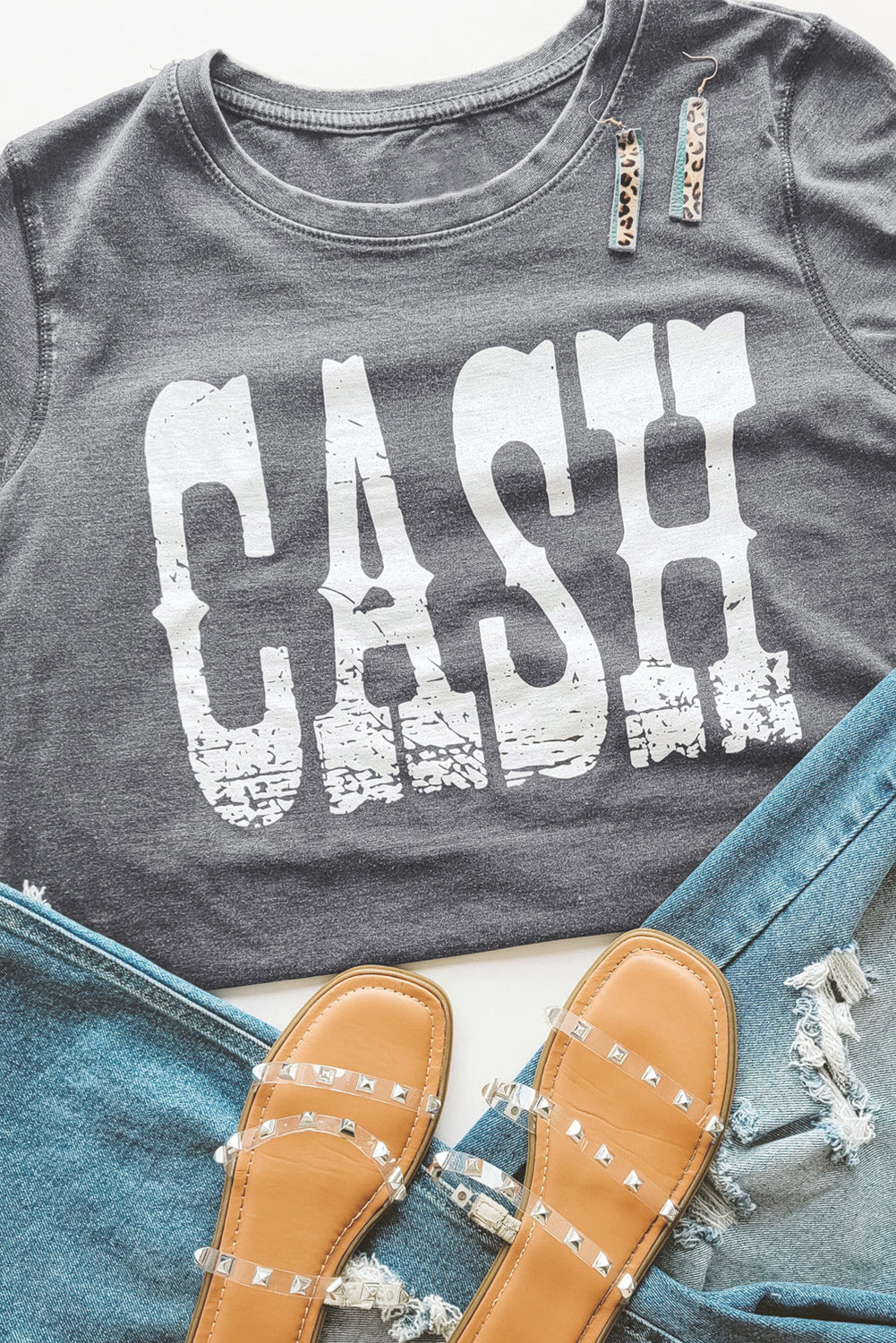 Gray t-shirt featuring a bold CASH letter print, showcasing a casual and stylish design suitable for everyday wear.