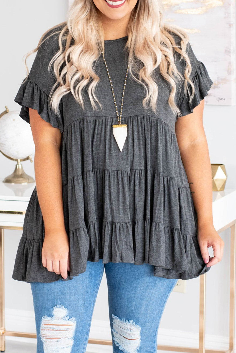 Gray tiered ruffled short sleeve plus size blouse displayed on a mannequin, showcasing its elegant design and comfortable fit.