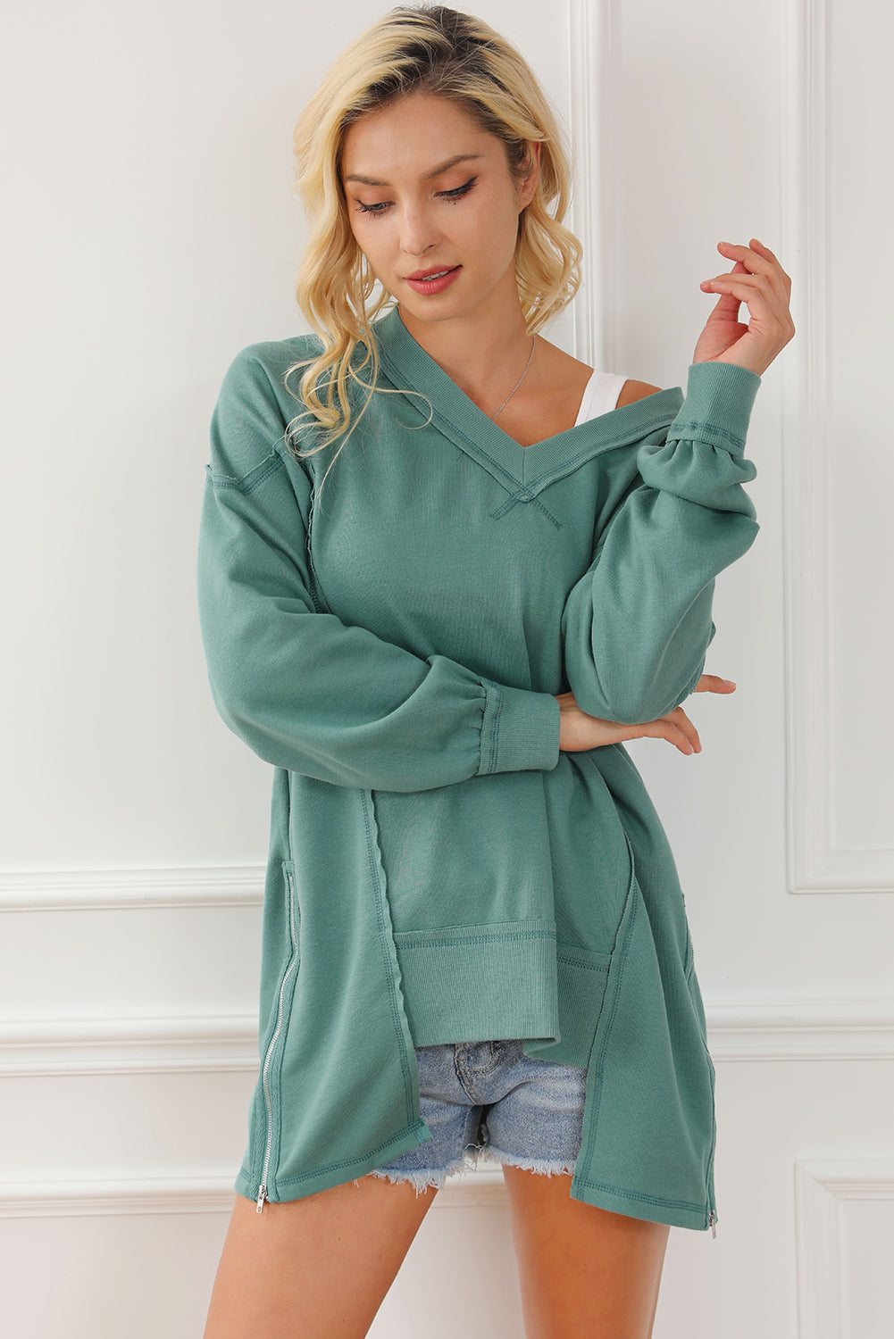 A stylish green high low sweatshirt featuring a V-neck and exposed seam detailing, perfect for casual wear.