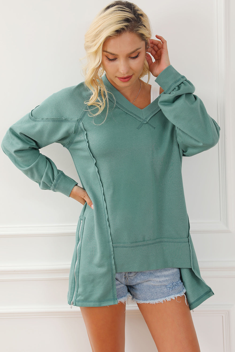 A stylish green high low sweatshirt featuring a V-neck and exposed seam detailing, perfect for casual wear.