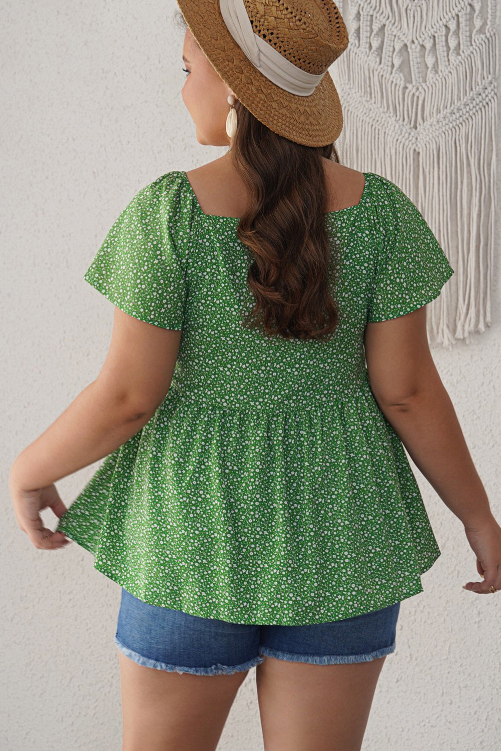 A stylish green plus size floral peplum top featuring a v-neck, flutter sleeves, and a flowy waist design, perfect for casual outings.