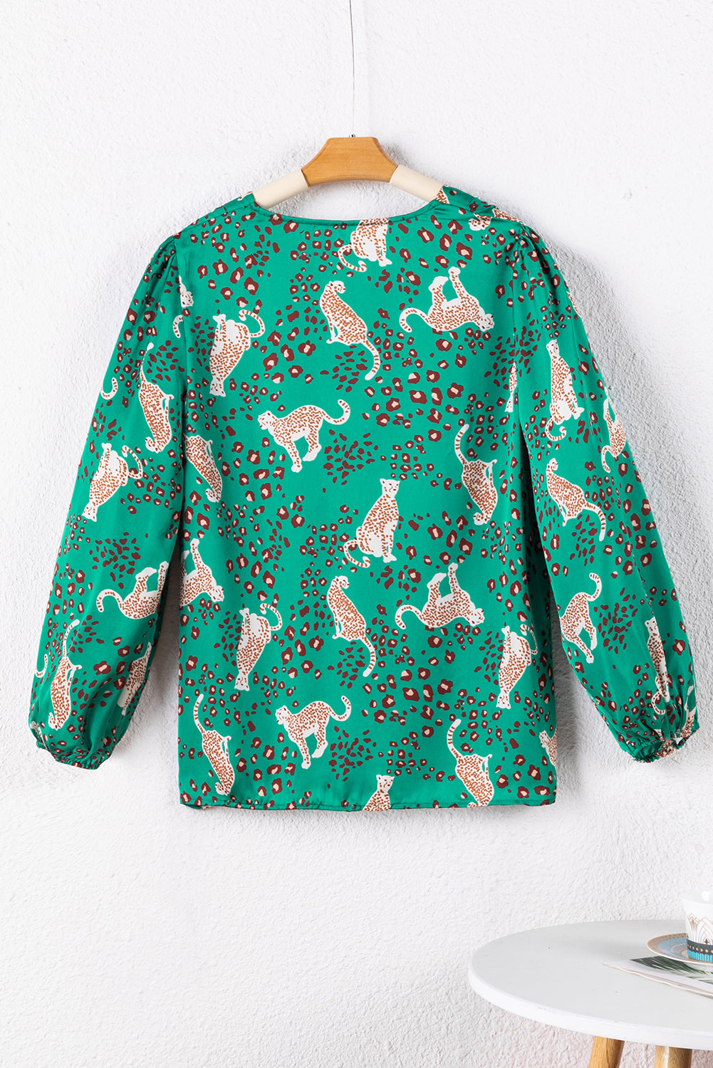 A stylish green blouse featuring a cheetah print design, V-neck, and flowy silhouette, perfect for casual wear.