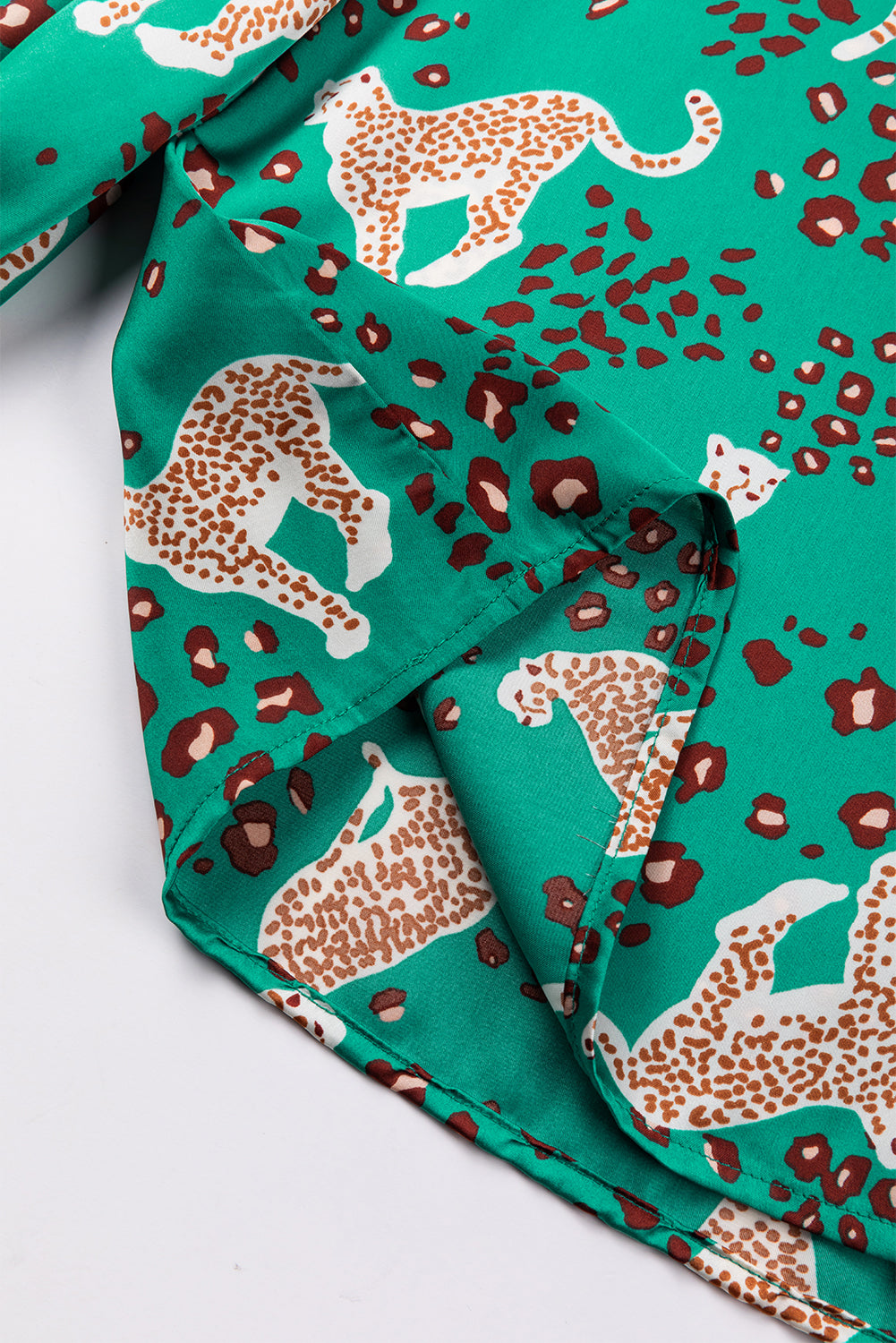 A stylish green blouse featuring a cheetah print design, V-neck, and flowy silhouette, perfect for casual wear.