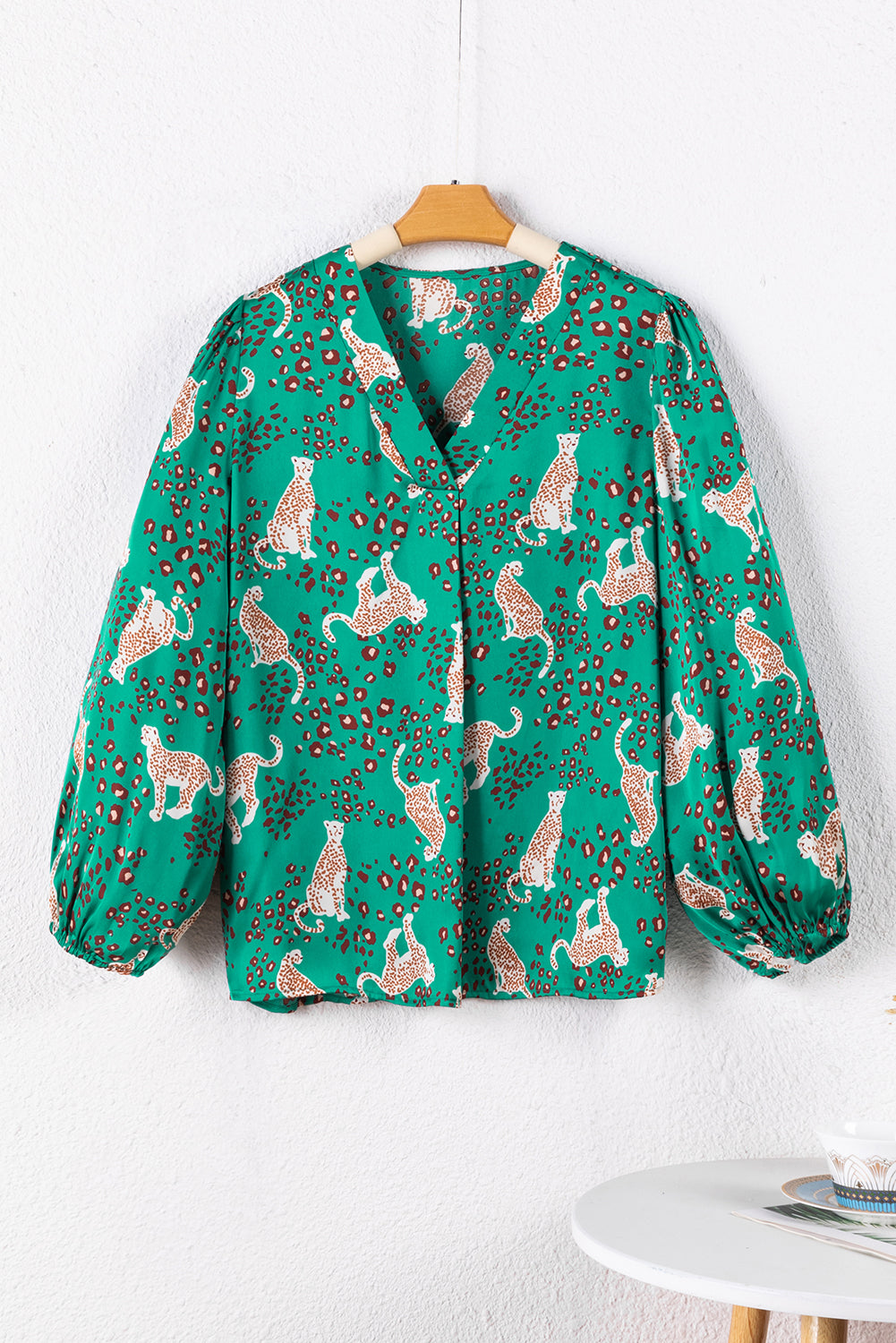 A stylish green blouse featuring a cheetah print design, V-neck, and flowy silhouette, perfect for casual wear.
